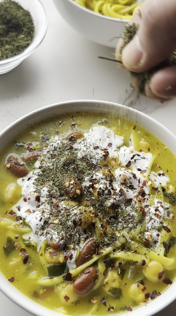 a bowl of aush/ash reshteh with red pepper flakes added